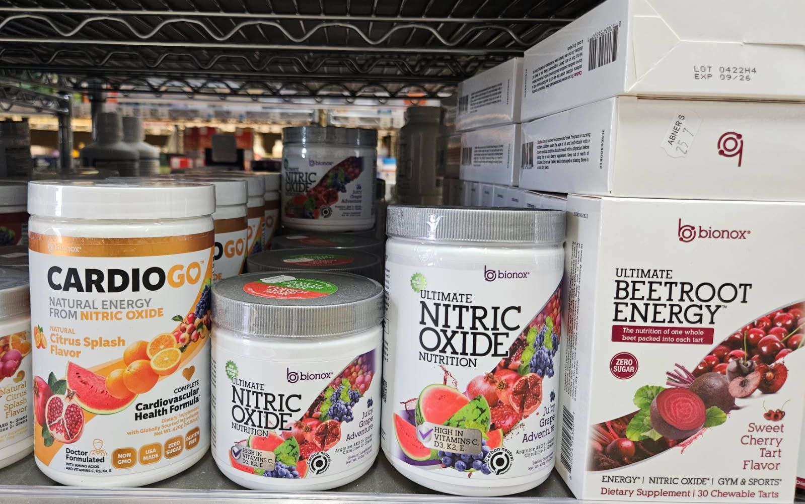 Shelves stocked with health supplements: CardioGo, Nitric Oxide, and Beetroot Energy containers.