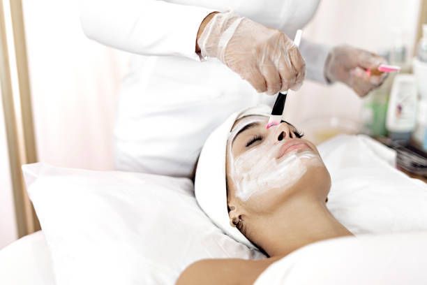 A woman is getting a facial treatment at a spa with face cream