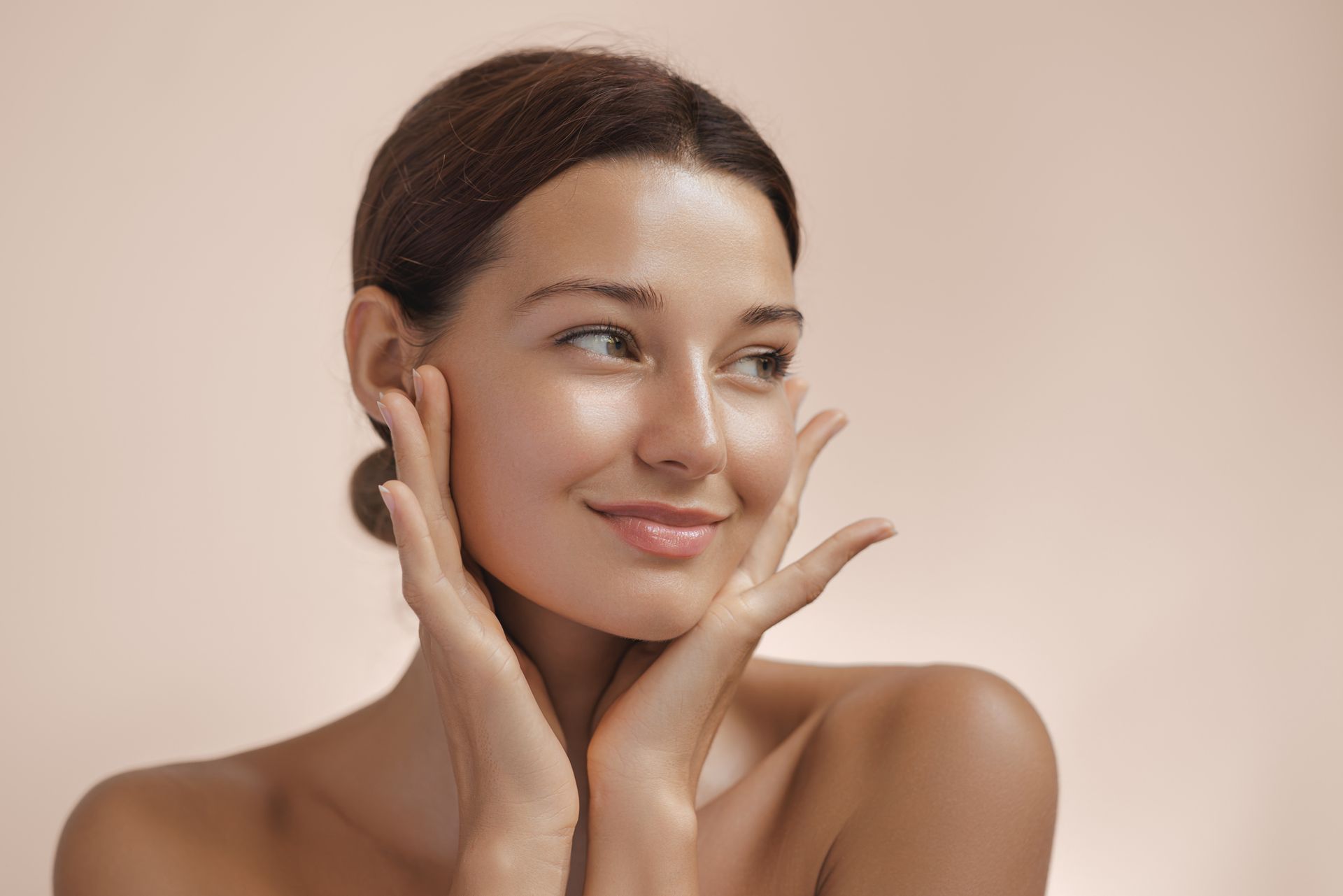 An older woman is touching her face with her hands and smiling.