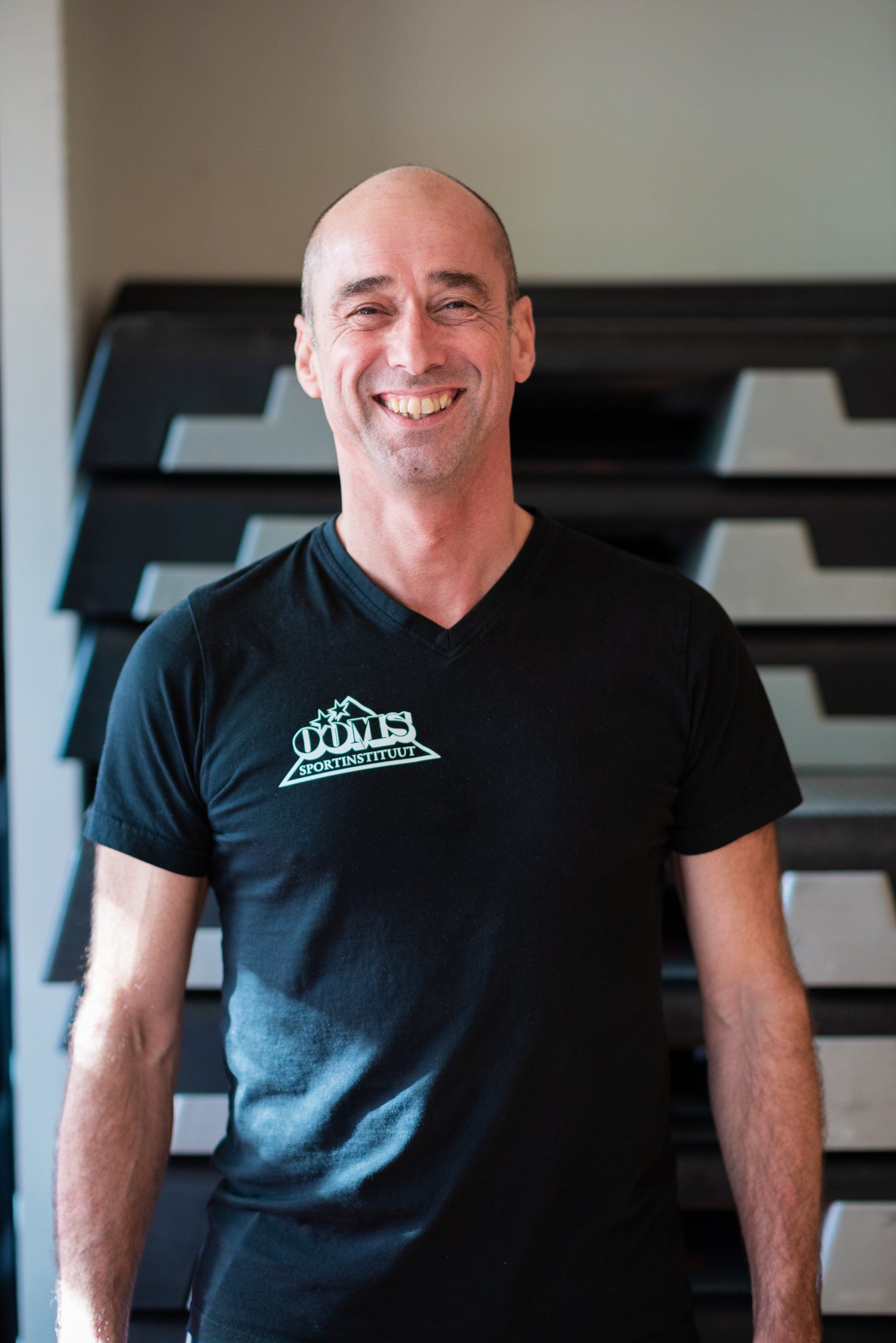 Een man in een zwart shirt glimlacht voor een stapel treden.