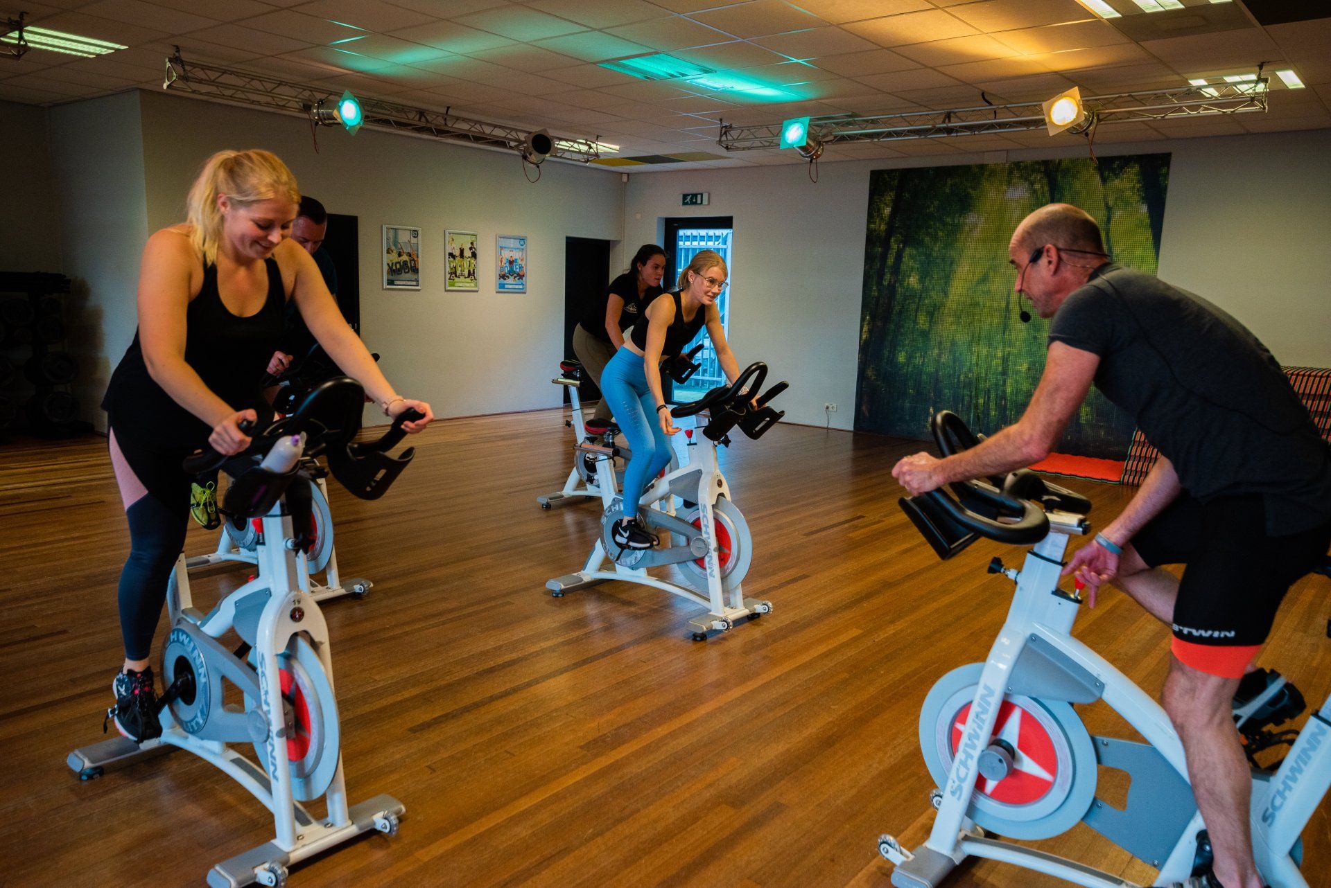 Een groep mensen rijdt op hometrainers in een sportschool.