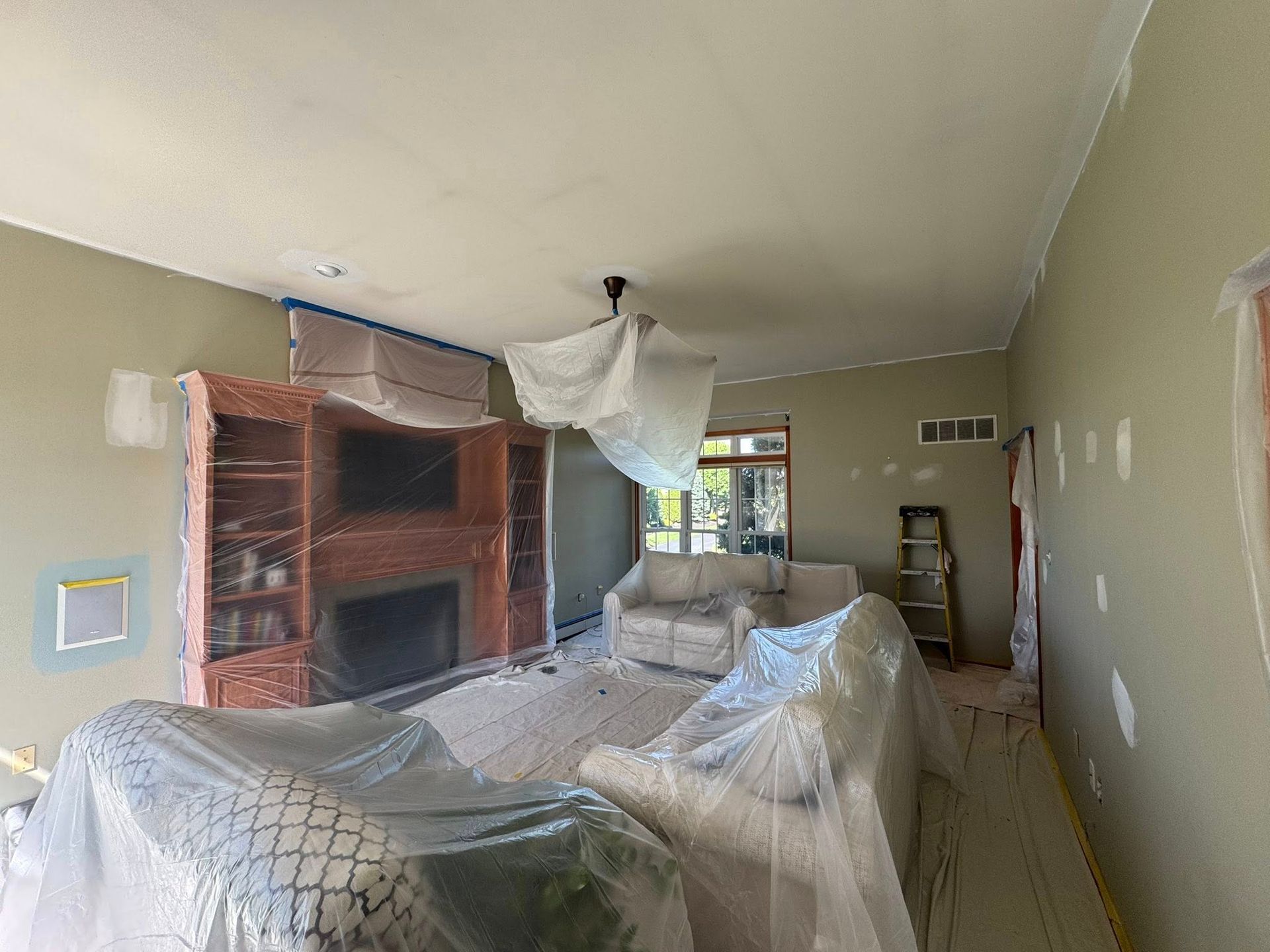 Picture of a living room prepped for painting, furniture covered and protected