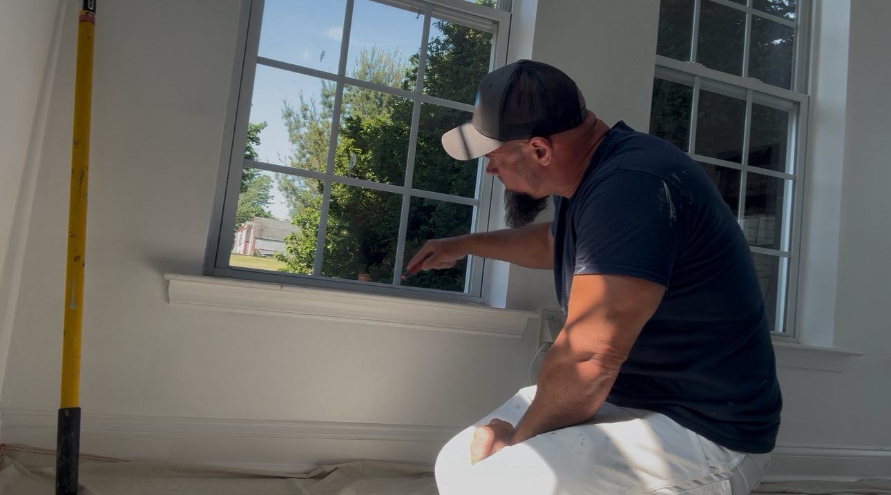 A person is holding a paint brush over a pink can.