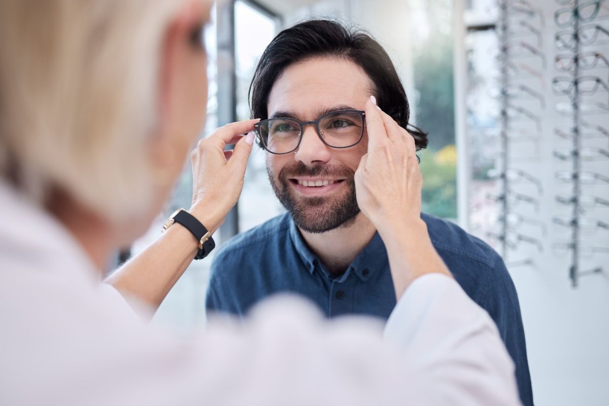 Optician adjusting eyeglasses on a customer in an optical shop.