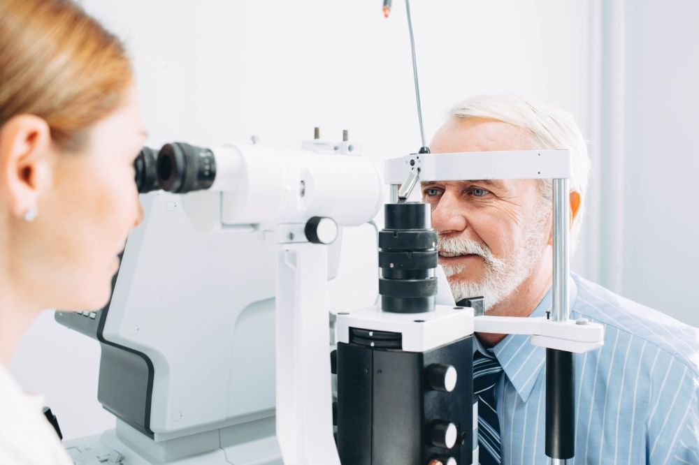 Optometrist examining a patient's eyes with a slit lamp.