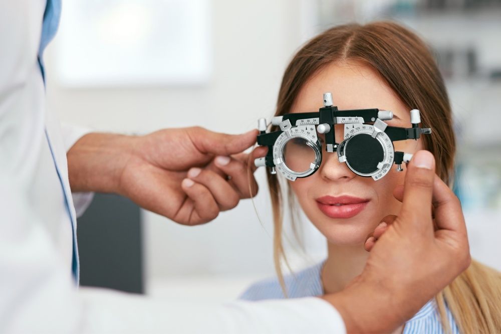 Optometrist adjusting a phoropter on a patient during an eye exam.