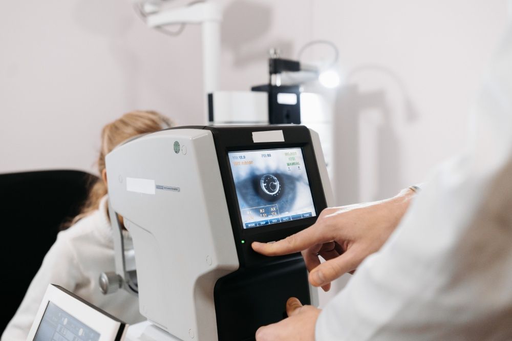 Eye doctor examining a patient's eye with a machine, showing the iris on a screen.