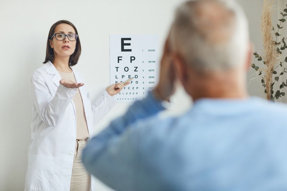 Optometrist pointing at eye chart, examining patient.