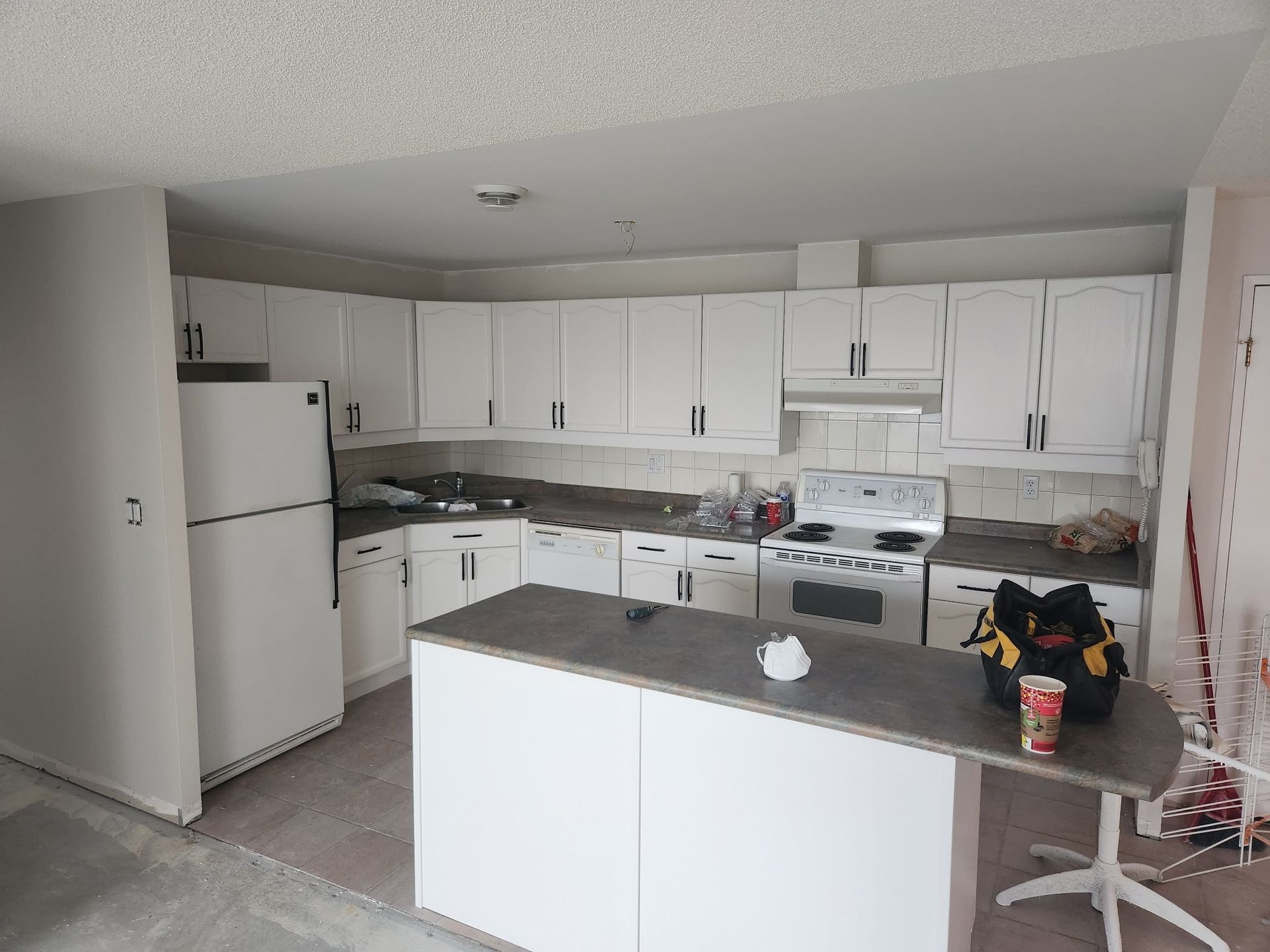 White kitchen with cabinets, island, and appliances under construction.