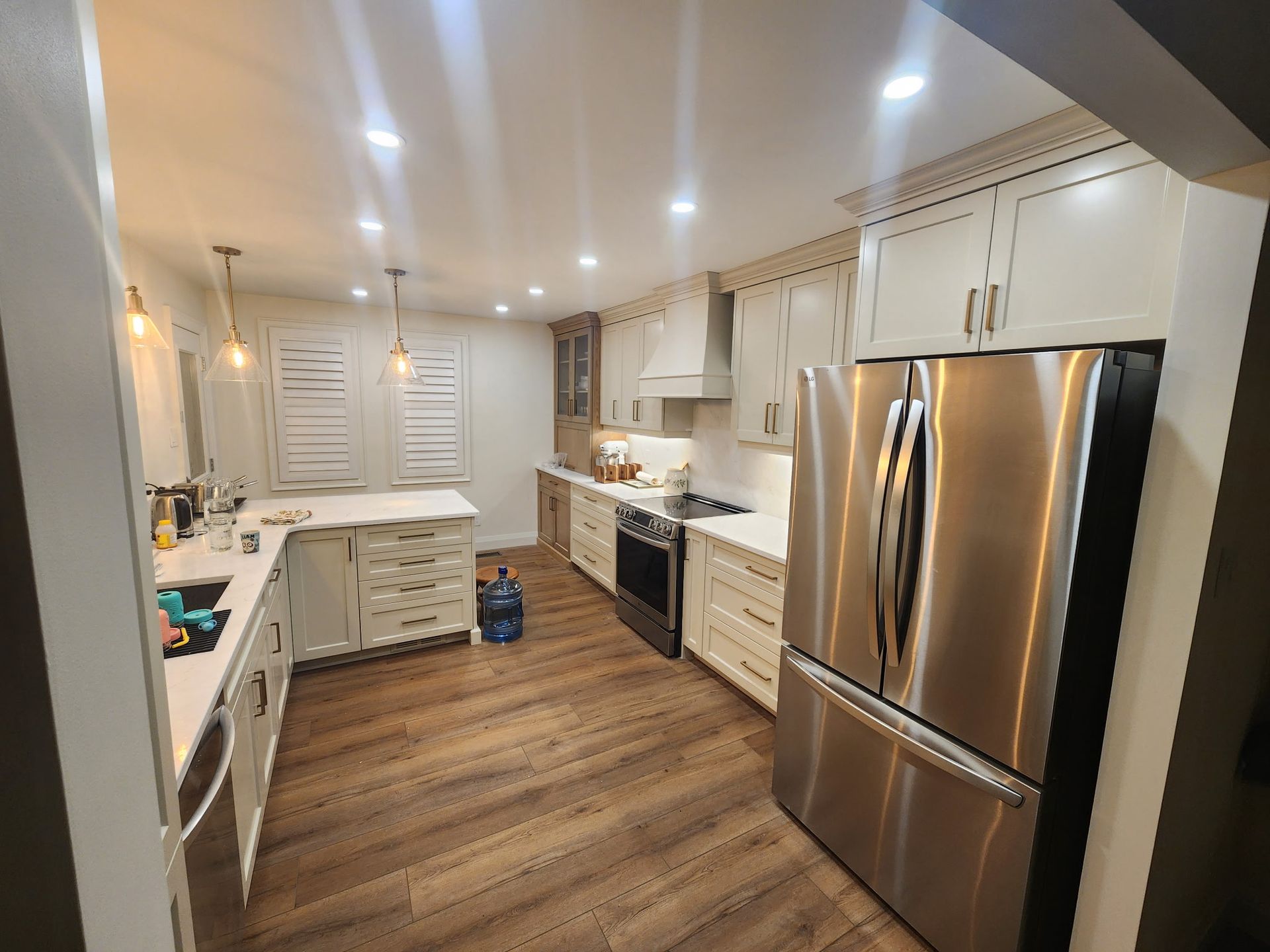 Modern kitchen with white cabinets, stainless steel appliances, and wood flooring.