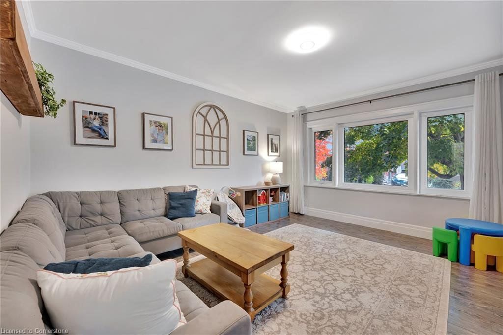 Cozy living room with a gray sectional, wooden coffee table, and large windows.  Light gray walls and a fluffy rug.