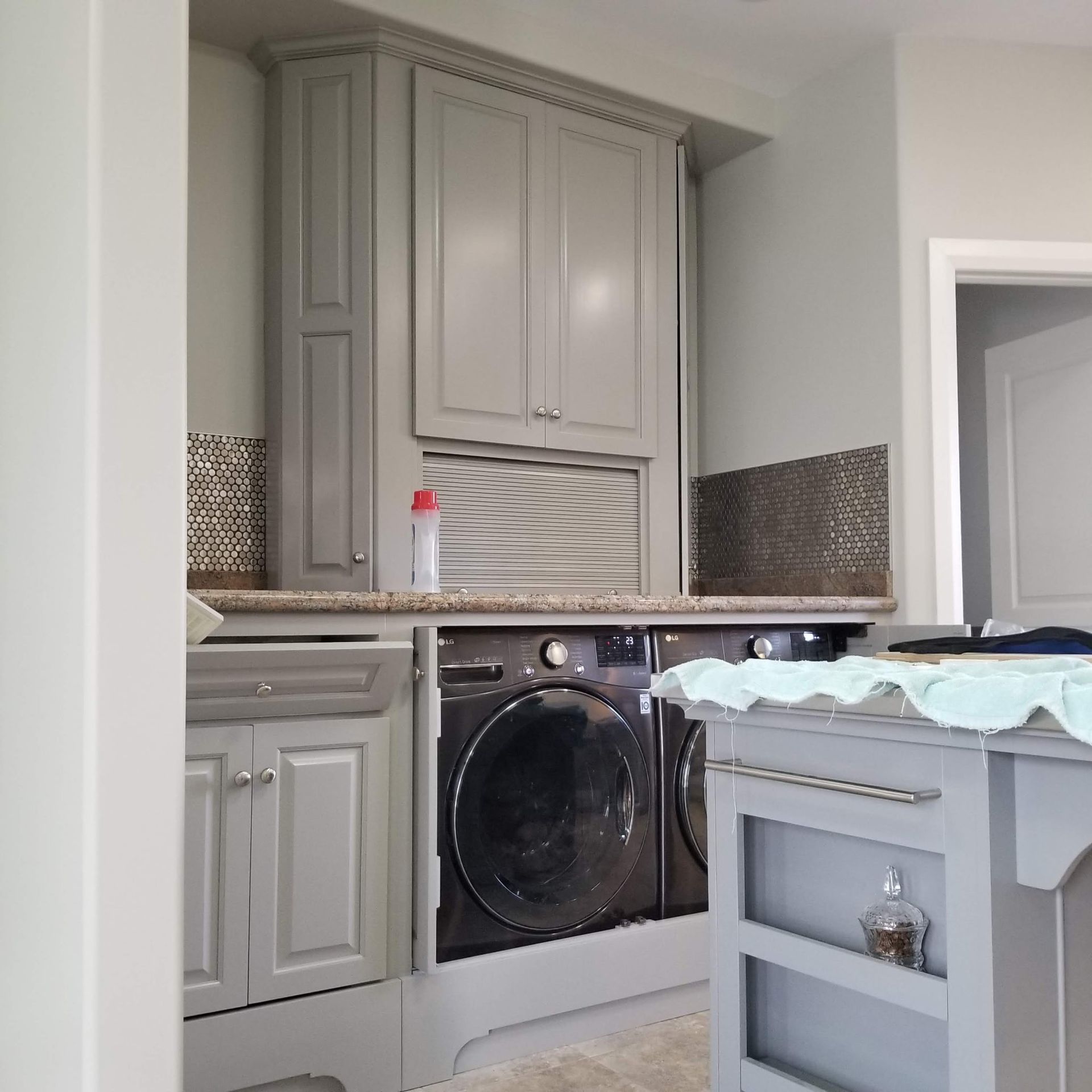 Laundry room with gray cabinets, washer/dryer, and a rolling cart.