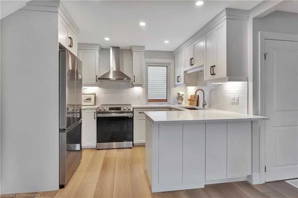 White kitchen with stainless steel appliances, light wood floors, and countertop.