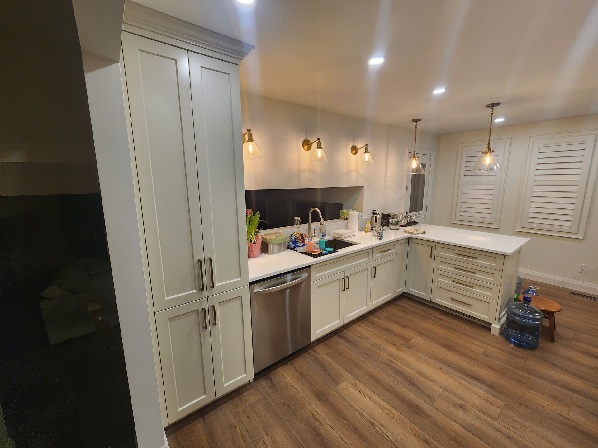 Modern kitchen with white cabinets, stainless steel appliances, and wooden floors.