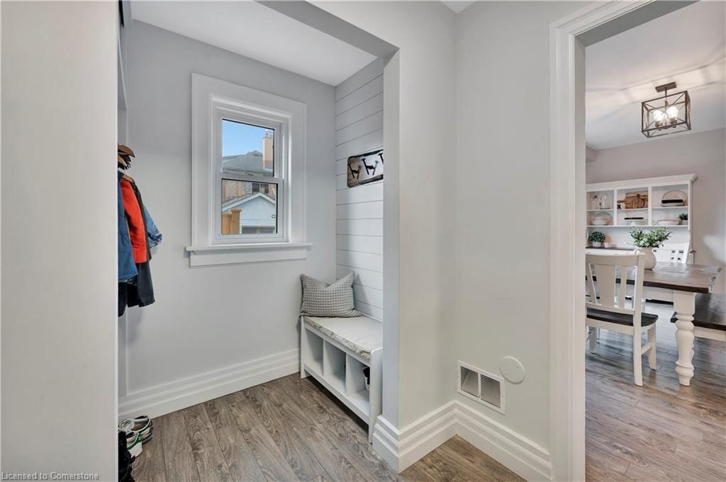 Entryway with bench, cubbies, window, and coats hanging. Light gray walls and wood-look flooring. Opens to dining room.