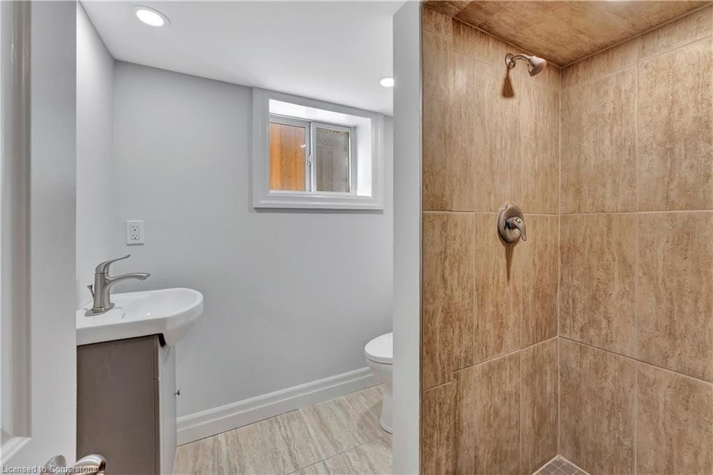 Small bathroom with a shower on the right. Sink and toilet are visible in the back.