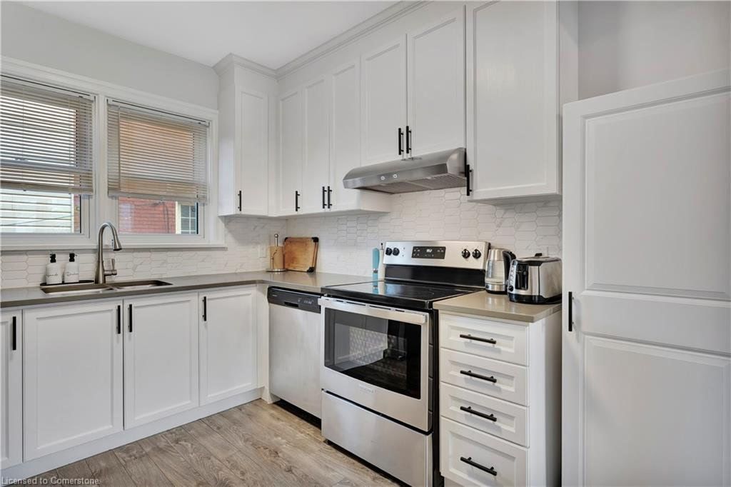 White kitchen with cabinets, stainless steel appliances, and roman shades.