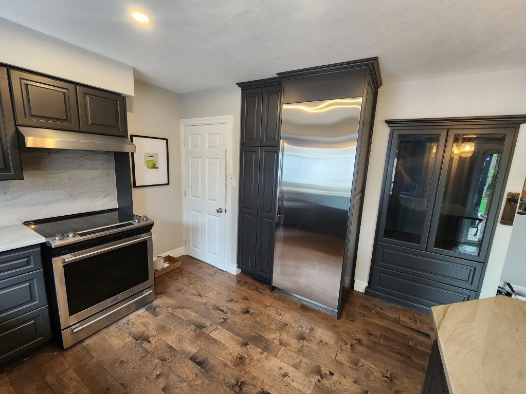 Kitchen with dark cabinets, stainless steel appliances, and wood flooring.