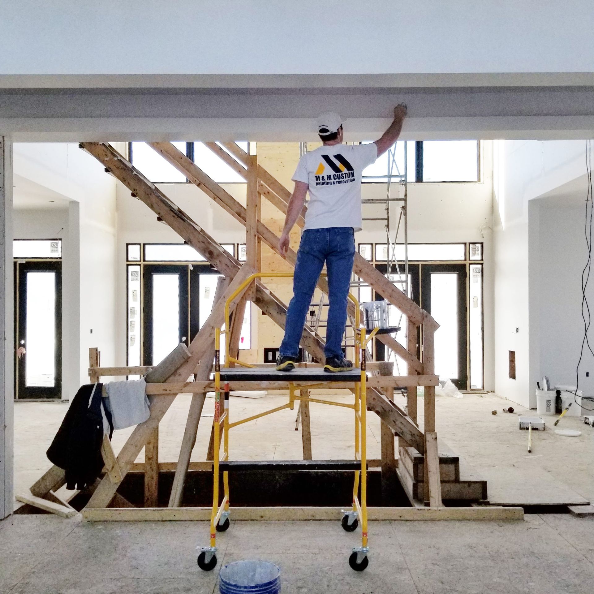 A construction worker on a scaffold reaches to work on a beam in a new home.
