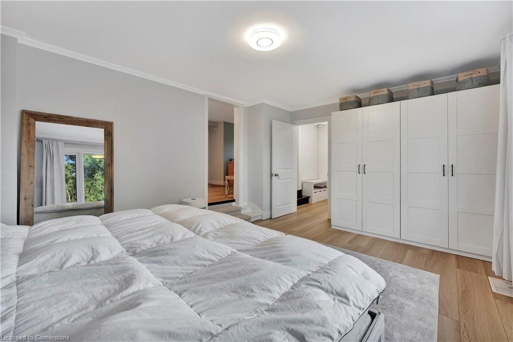 Bedroom with a white bed, large mirror, white wardrobe, and light wood flooring.