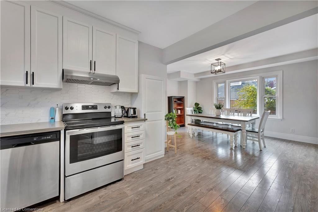 Kitchen and dining room with stainless steel appliances, white cabinets, and wood flooring.