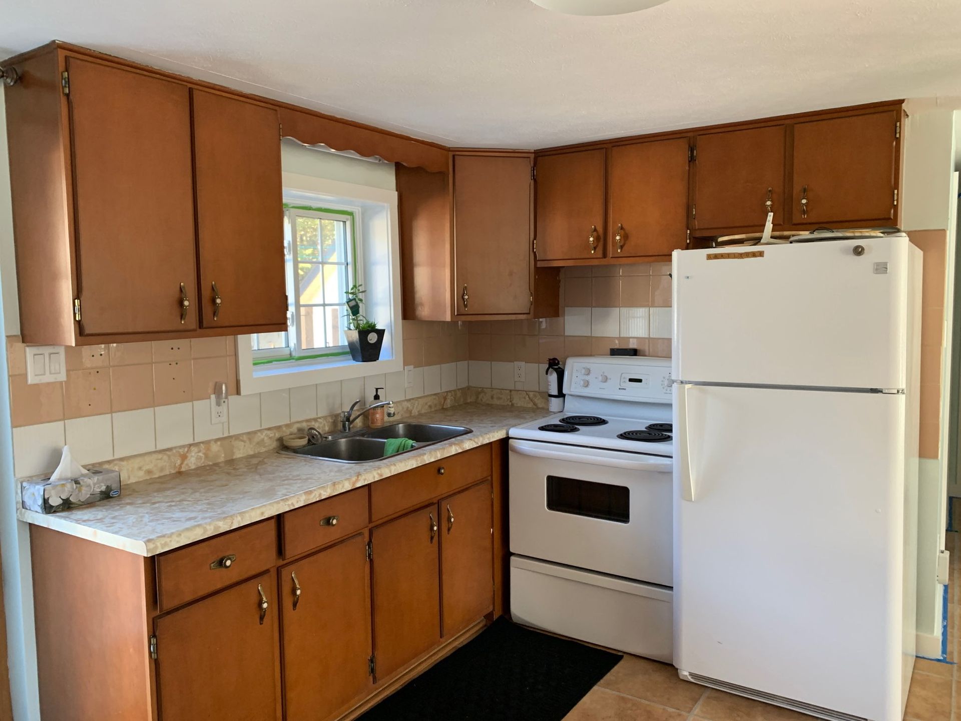 Kitchen with brown cabinets, white appliances, and a window above the sink.