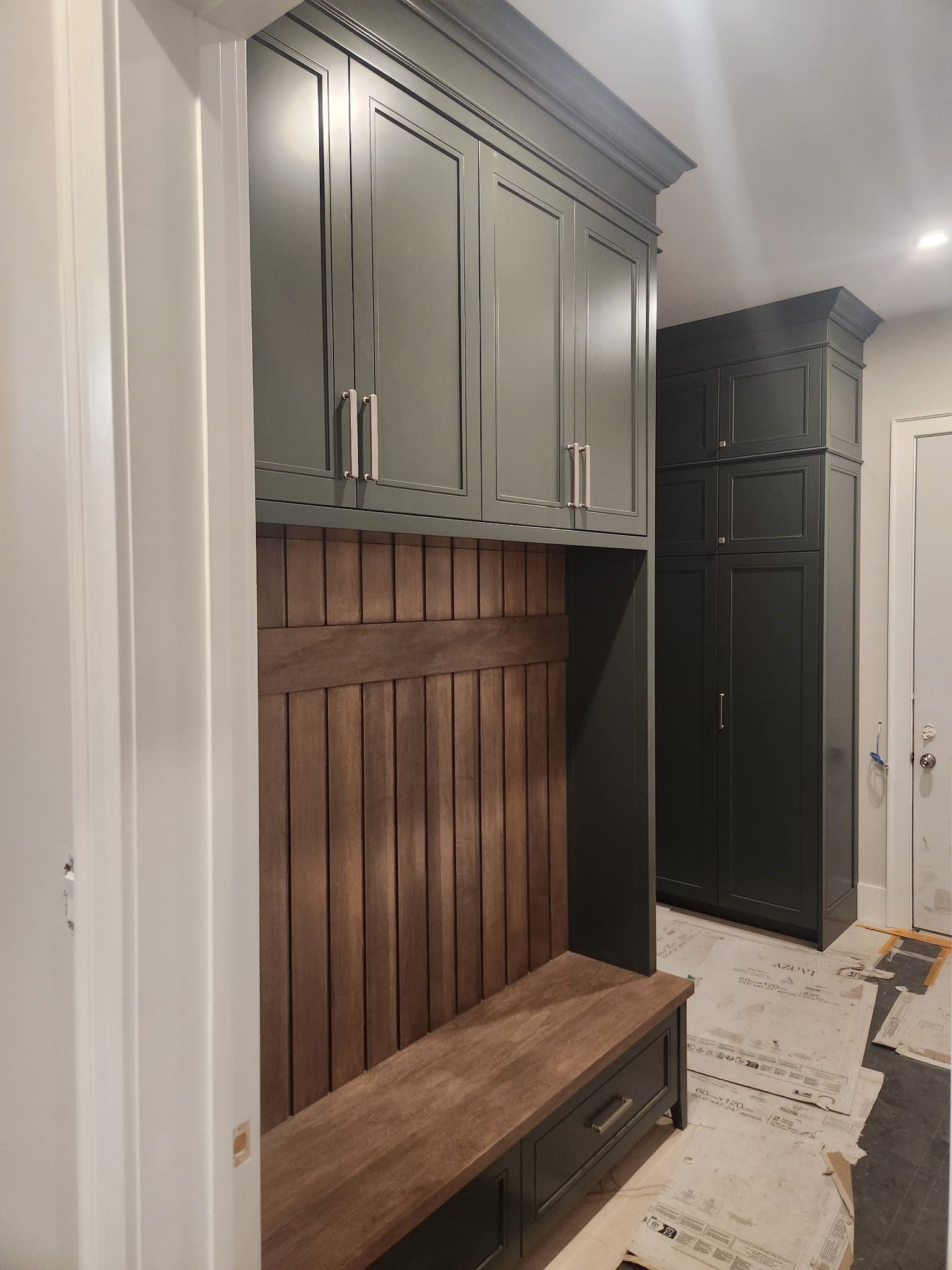 Dark green built-in cabinetry and bench with wood accents in a hallway.