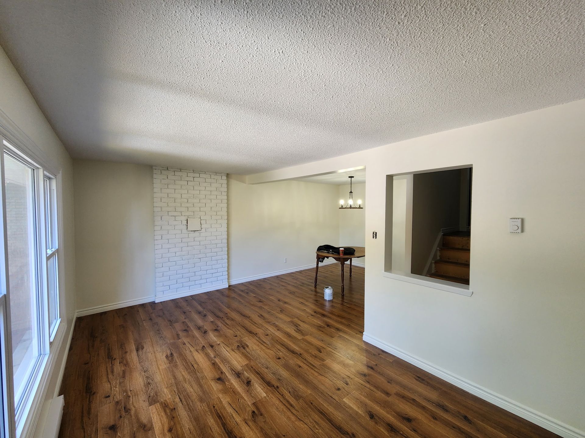 Empty living room with wood flooring, white walls, and a textured ceiling.