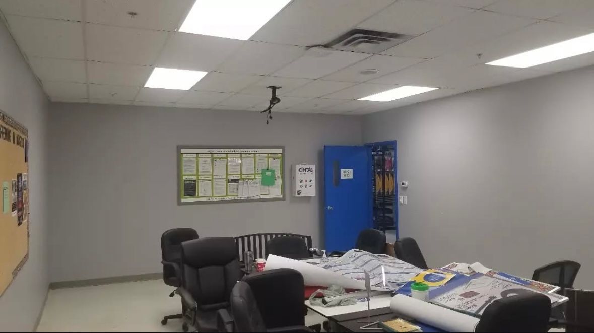 A mostly empty office with a conference table, chairs, and a blue cabinet.