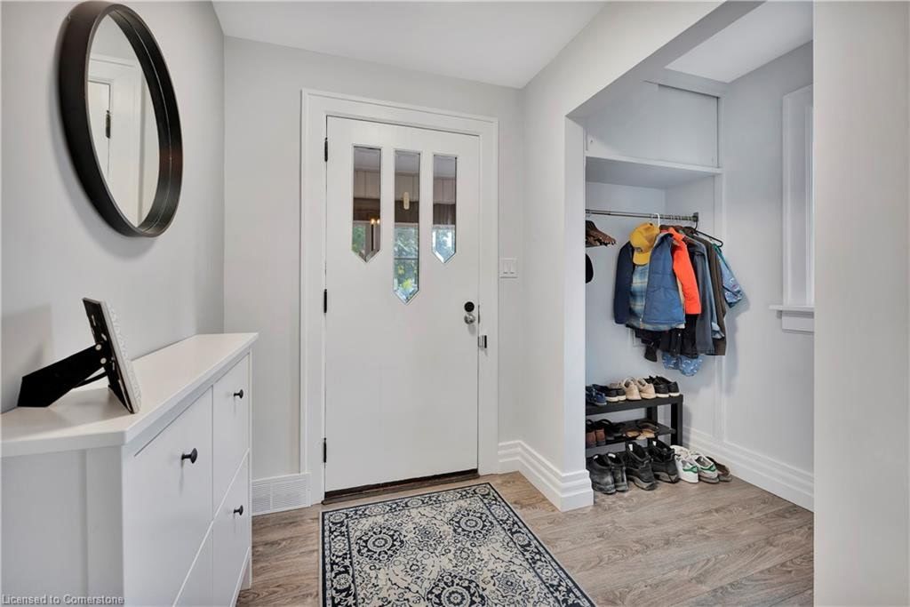 Entryway with white door, rug, mirror, shoe storage, and coat rack.