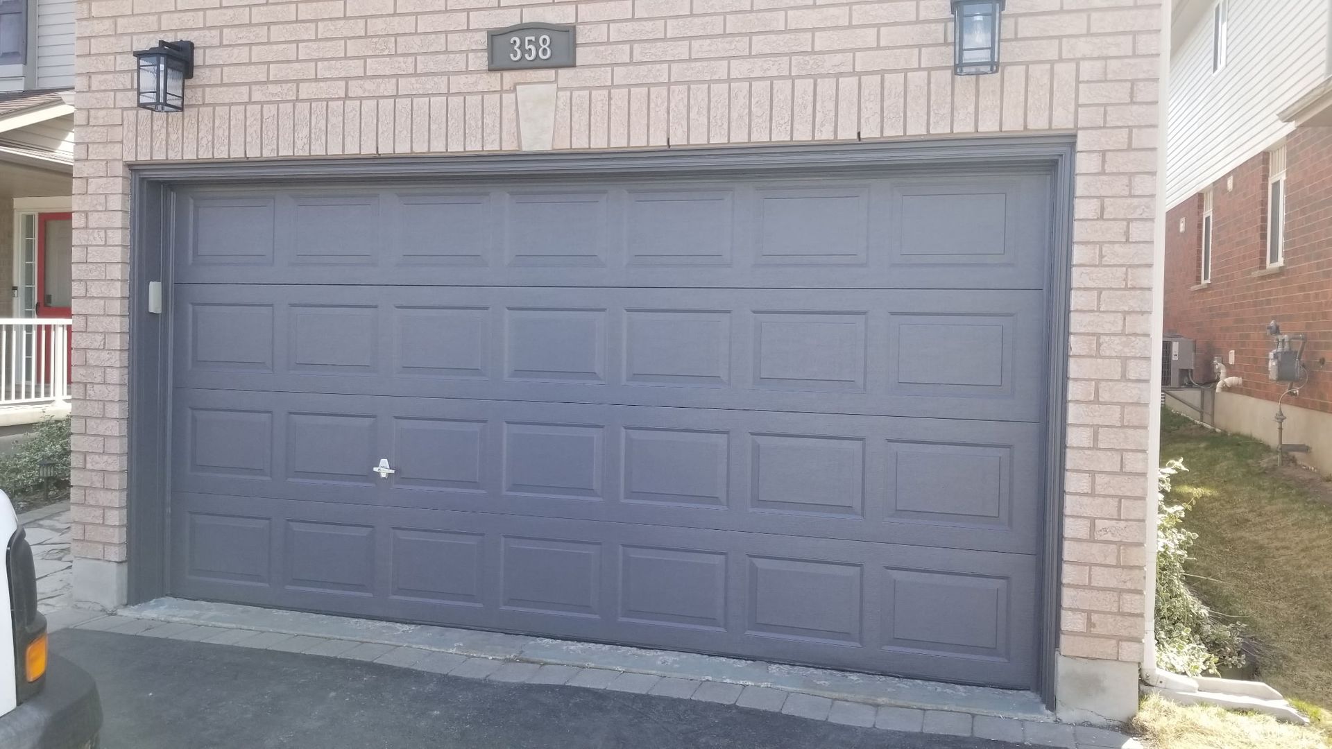 Gray garage door with brick facade, two lights, and house number 335.