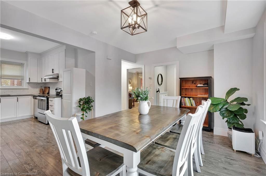 Dining room with a wooden table and white chairs, connected to a kitchen.