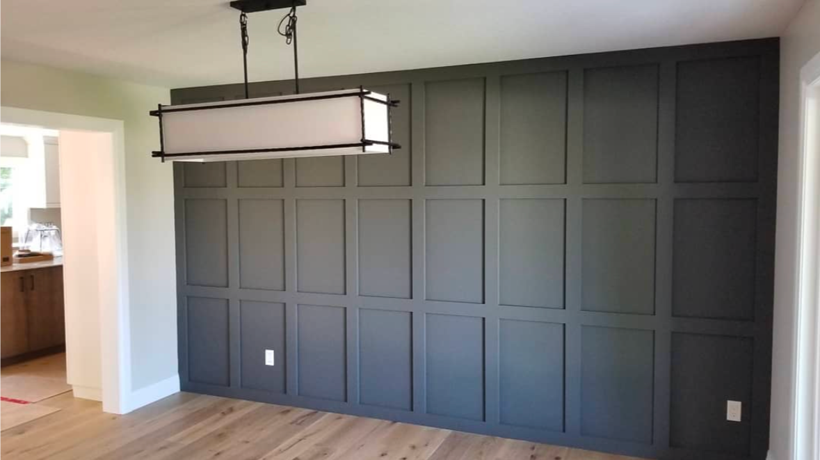 Dark gray paneled accent wall with a rectangular light fixture; wood floor.