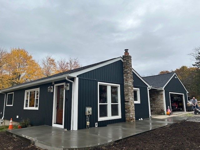 A blue house with white trim and a stone chimney. - Gibsonia, PA - Langell Concrete Construction