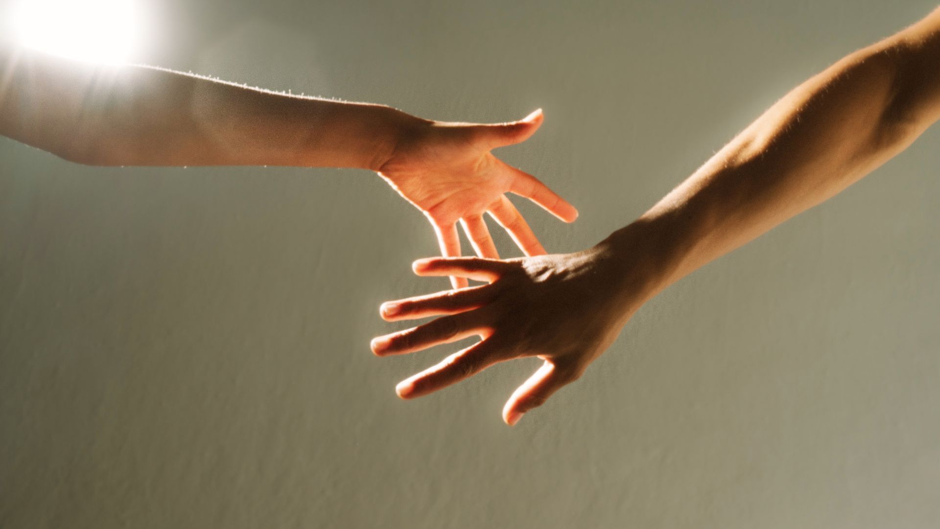 Two women on a sofa, one speaking, gesturing with pen. Interior setting.