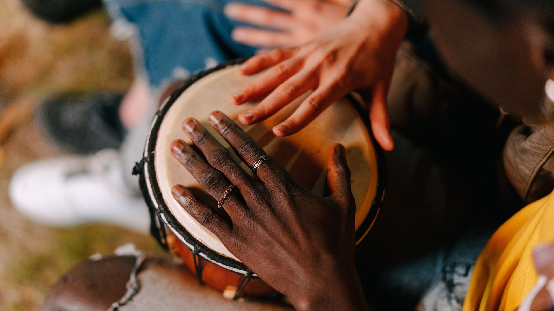 Woman playing a large gong over a person lying down, possibly for sound healing.