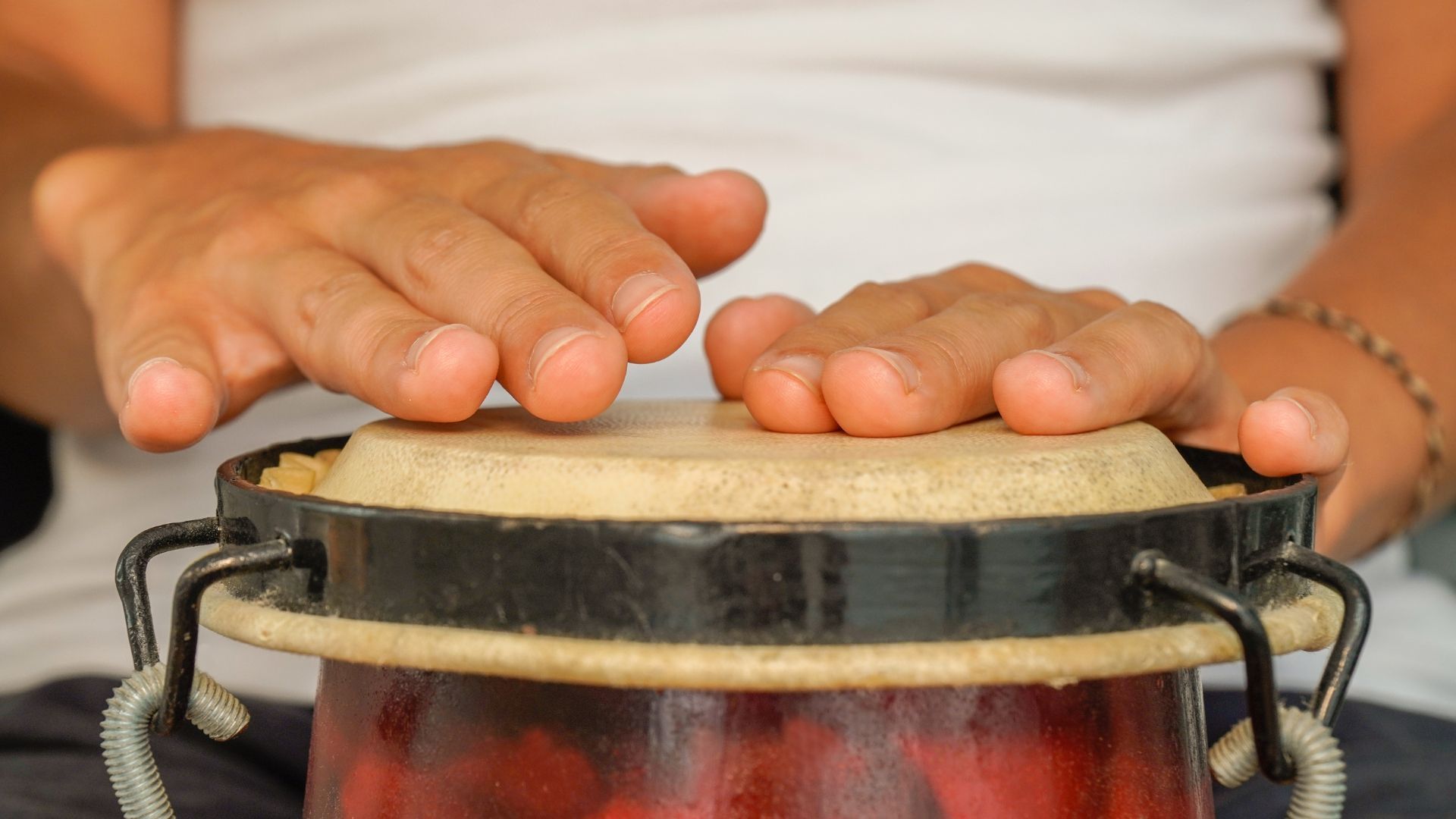 Hands drumming on a small conga drum.