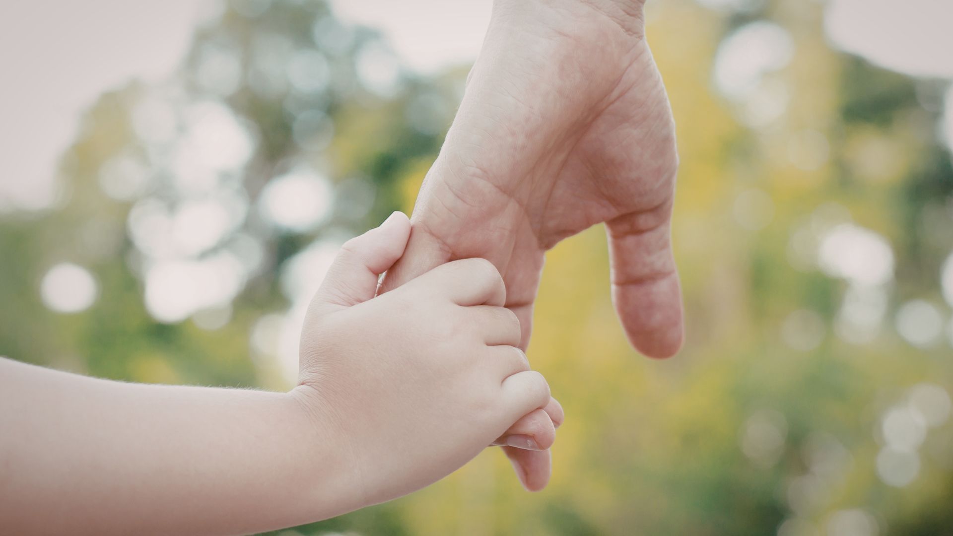 Woman taking notes, talking to a child on a couch, a teddy bear rests beside the child.
