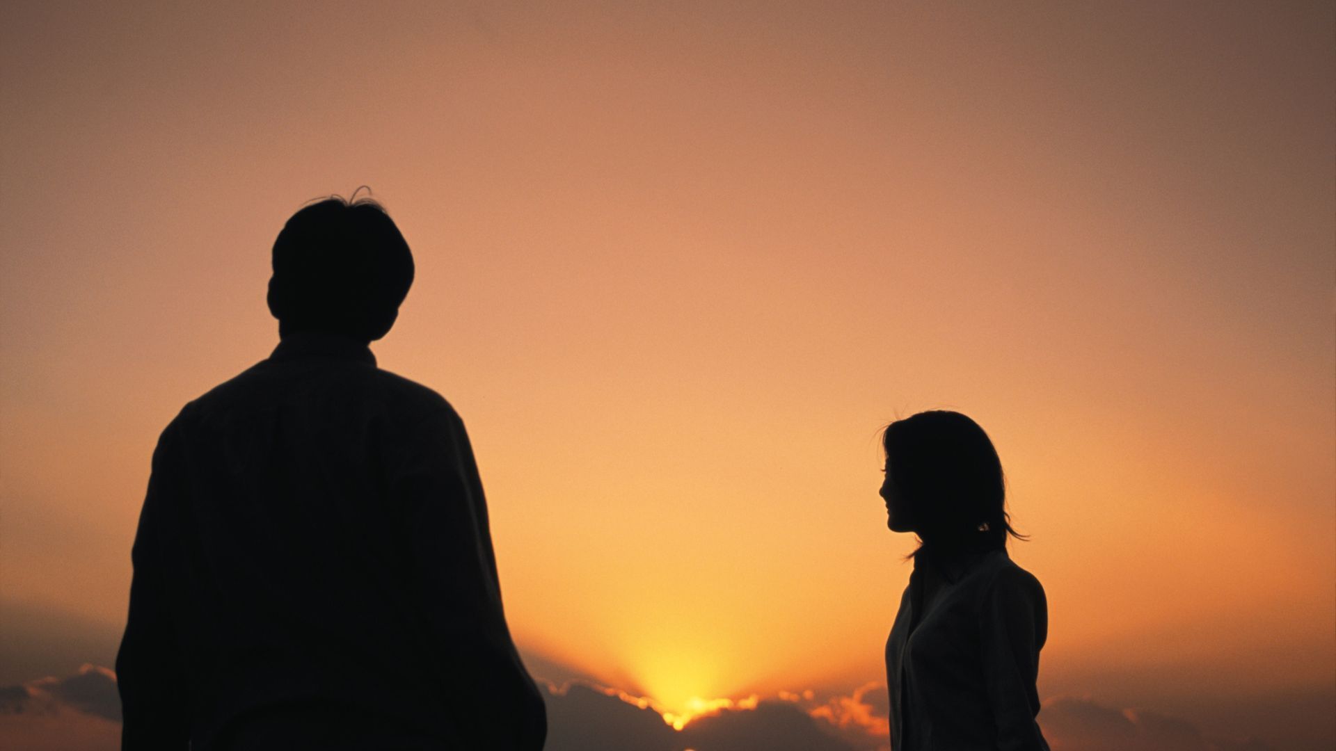 Silhouette of two people arguing in front of a window with curtains.