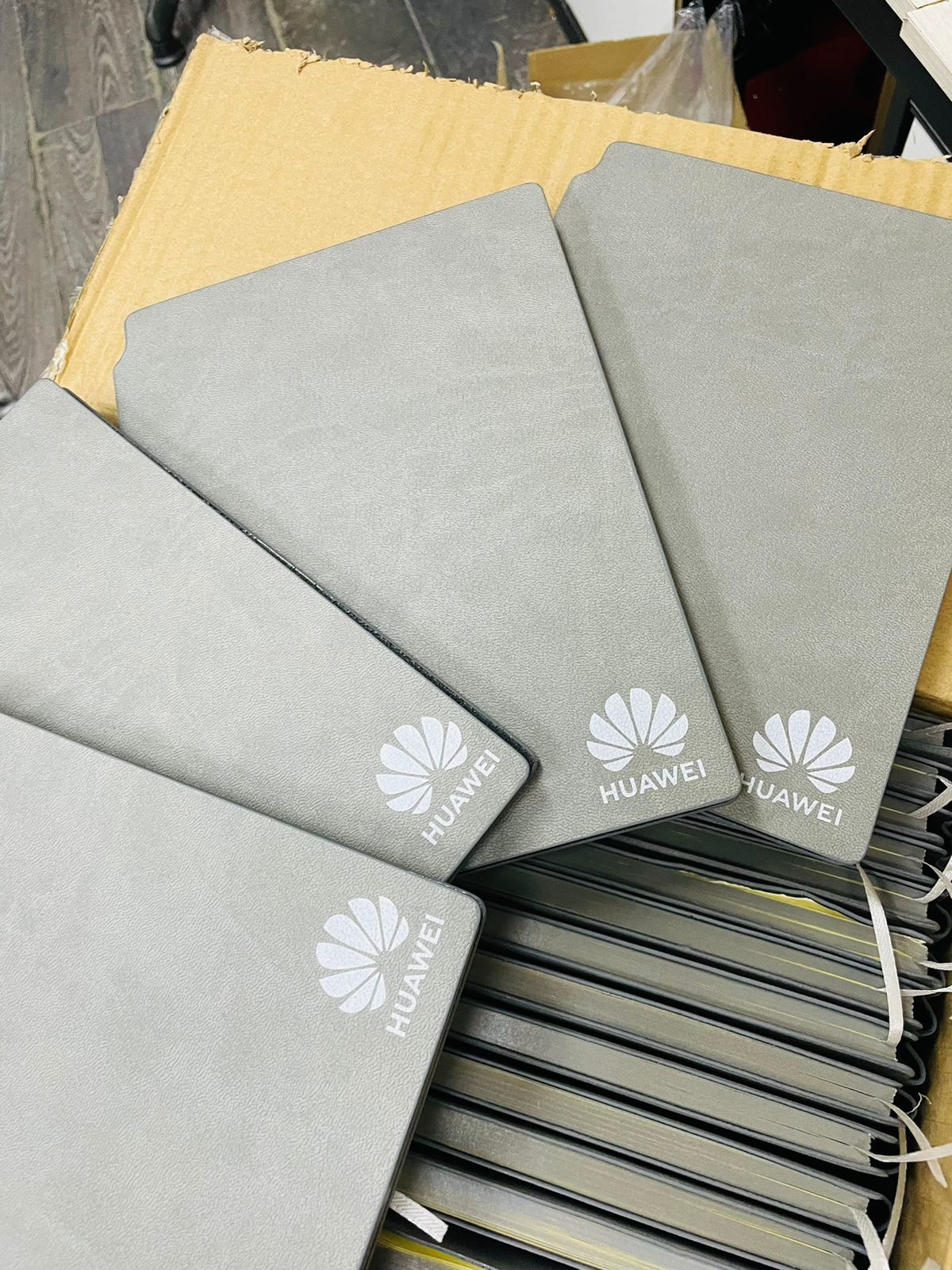 Fundas grises de la marca Huawei apiladas en una caja de cartón.