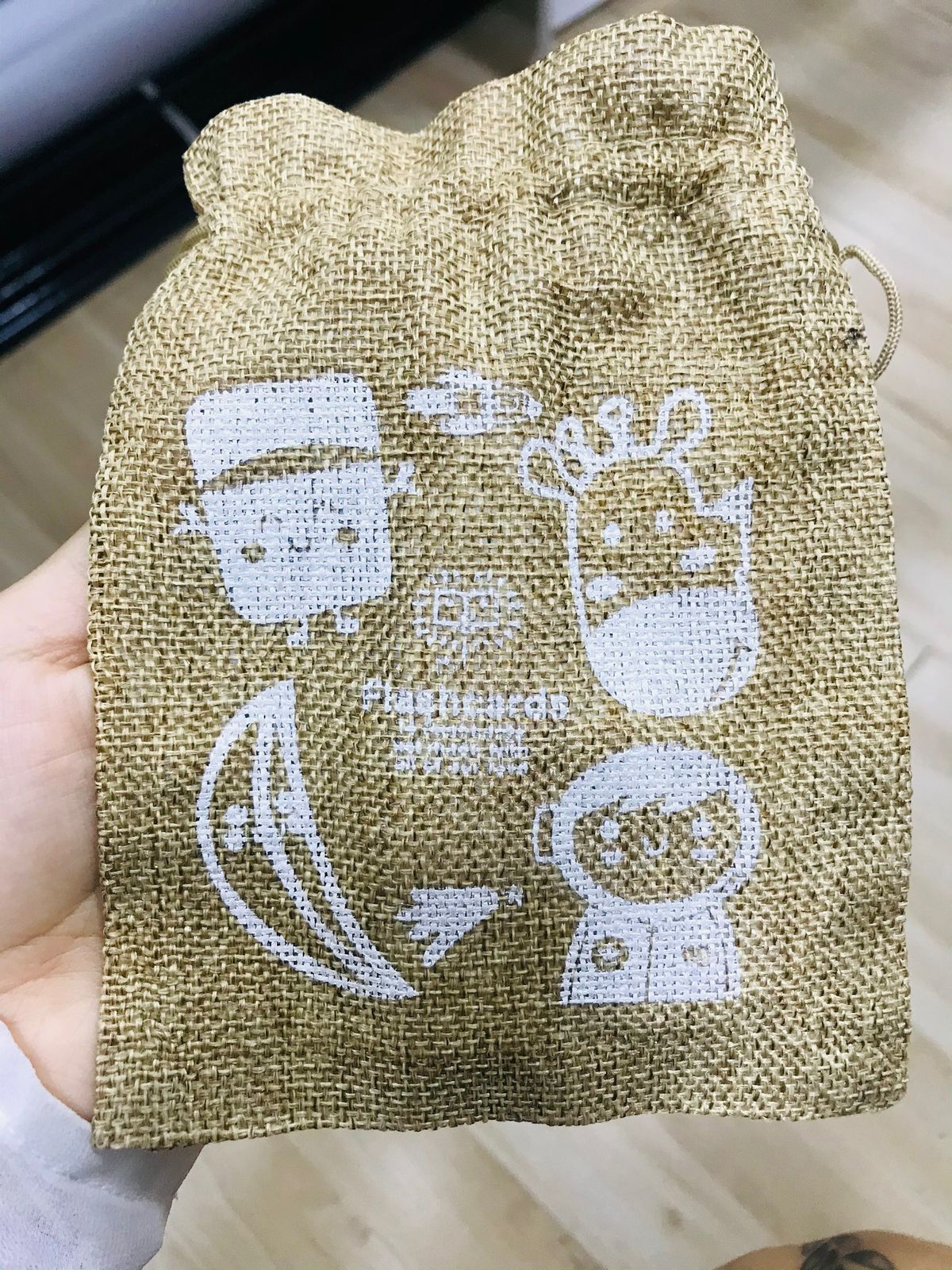 Bolsa de arpillera de color marrón con imágenes de dibujos animados en blanco: Frankenstein, reno, astronauta, plátano.