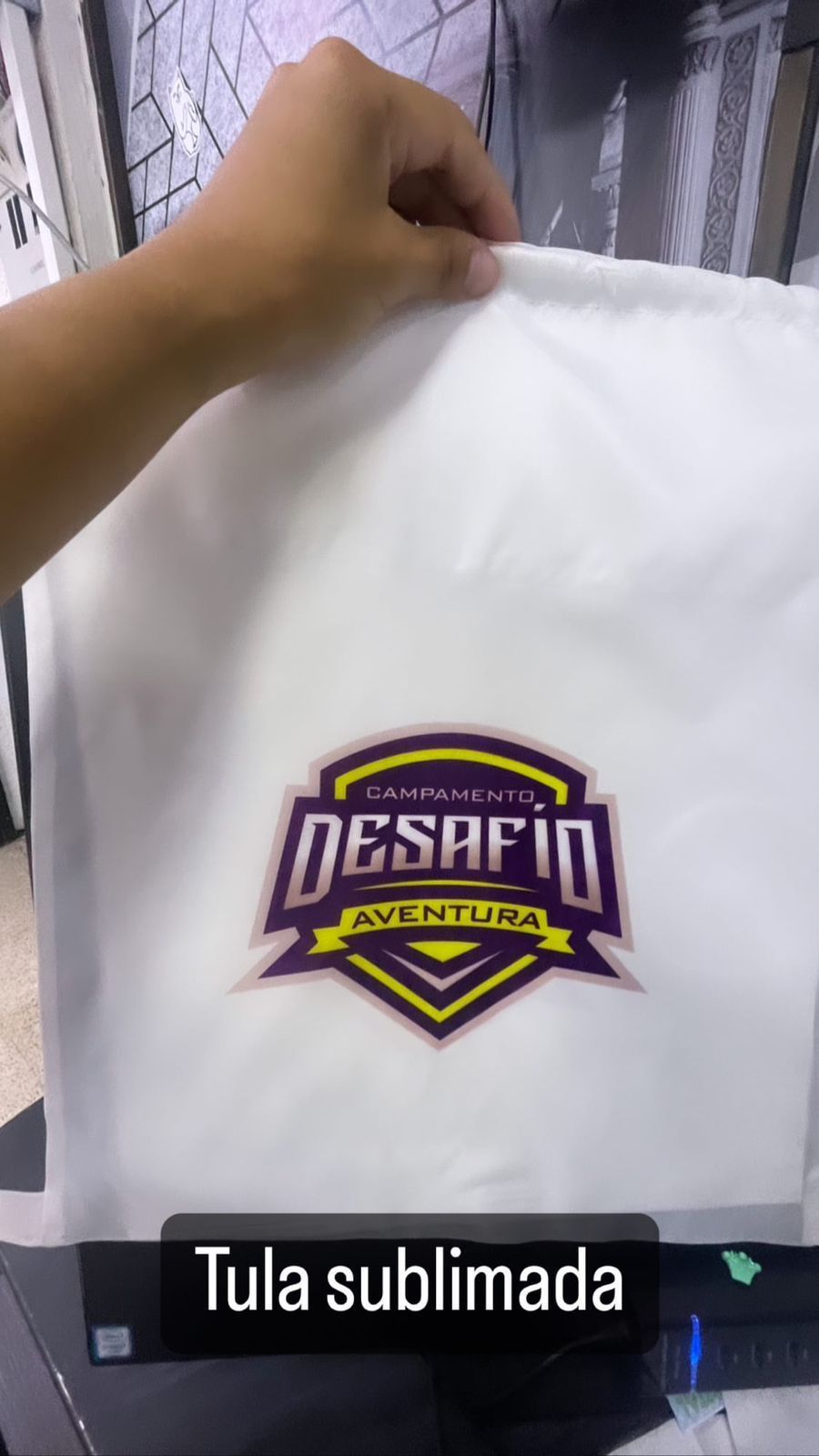 Mano sosteniendo una bolsa con cordón blanca estampada con un logo 
