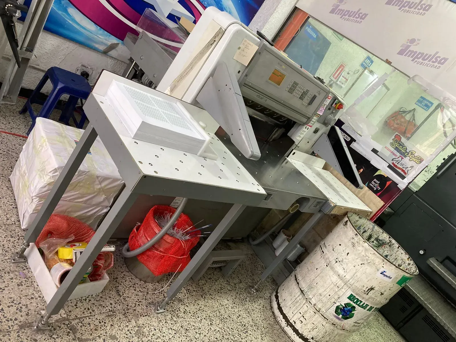 Máquina guillotina de papel en una imprenta, con una pila de papel lista para ser cortada.