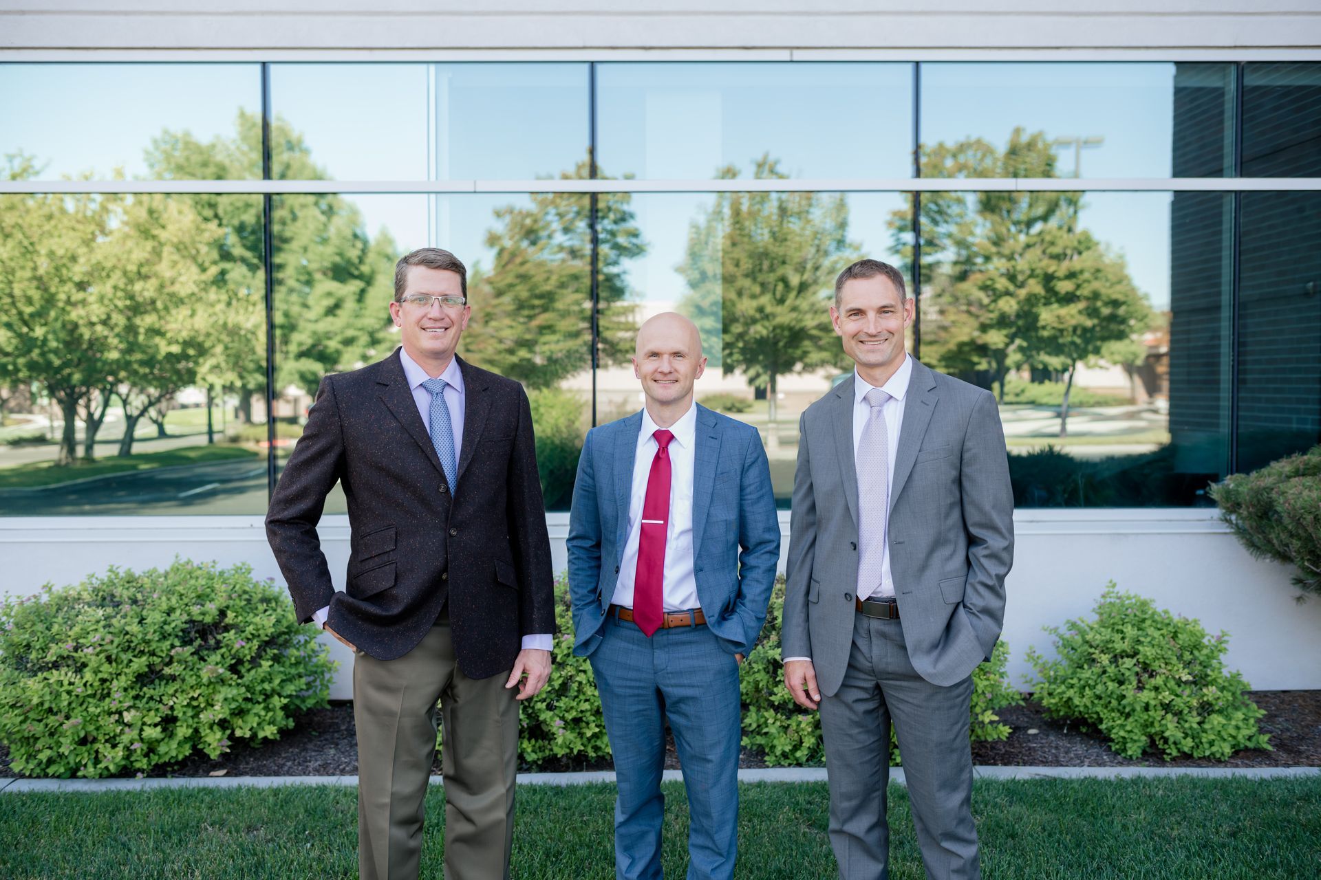 Four men in suits stand outside. They smile at the camera.