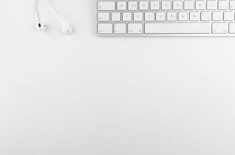 White keyboard and earbuds on a white background.