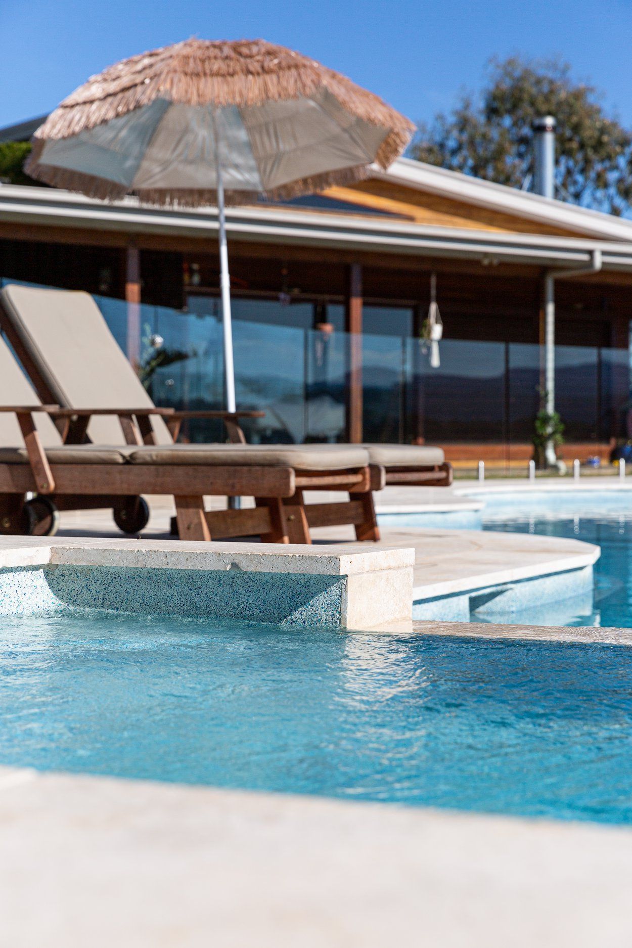 A Large Swimming Pool Surrounded By Trees And A Wooden Deck — Profile Pools & Landscaping In Kingscliff, NSW