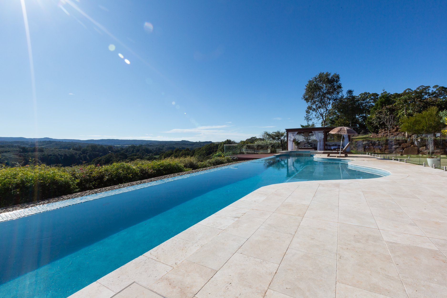 A large Swimming pool with a View of a forest on a Sunny day — Profile Pools & Landscaping In Byron Bay, NSW
