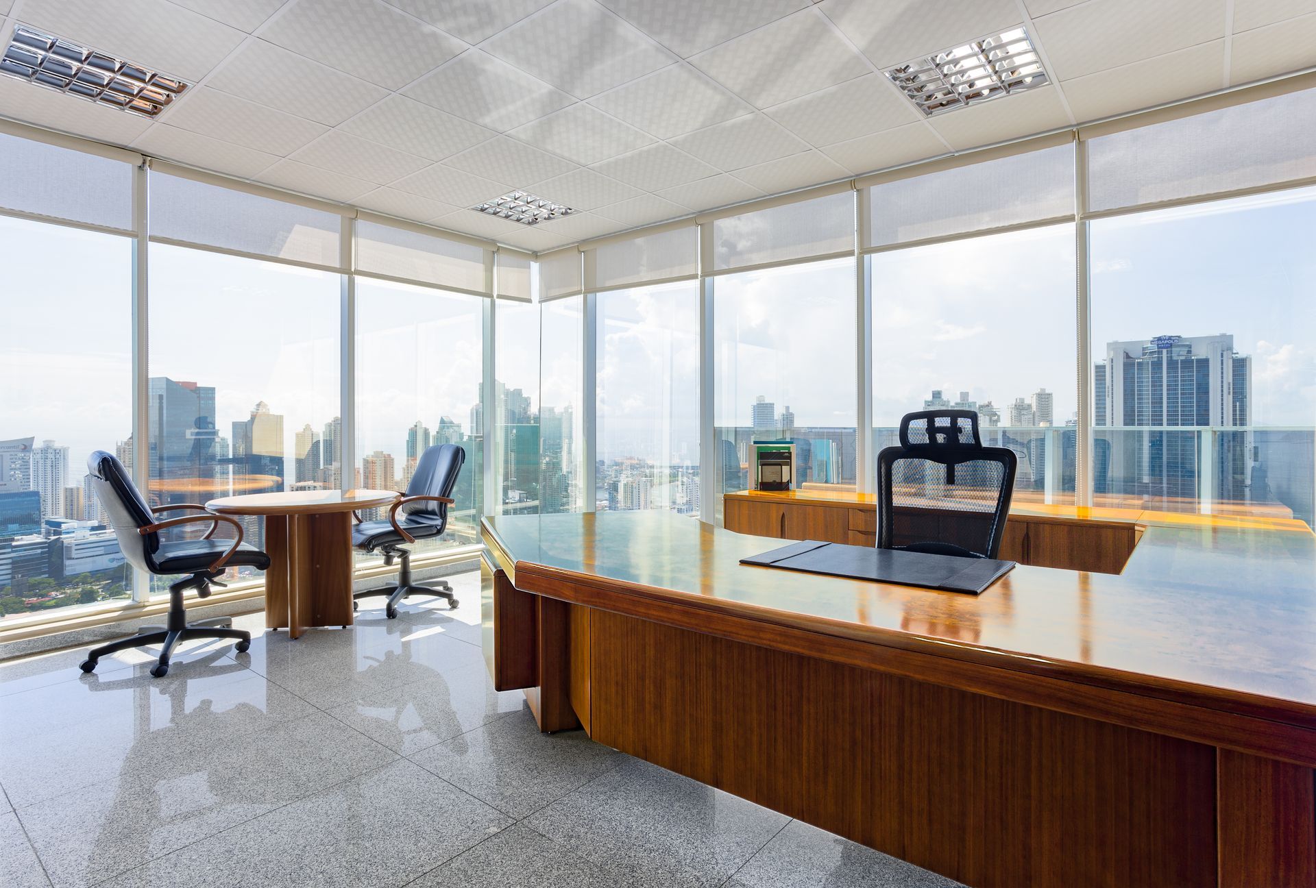 Una oficina grande con un gran escritorio y sillas y muchas ventanas.