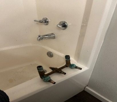 A bathtub with faucets and a disassembled copper plumbing fixture visible inside the tub.
