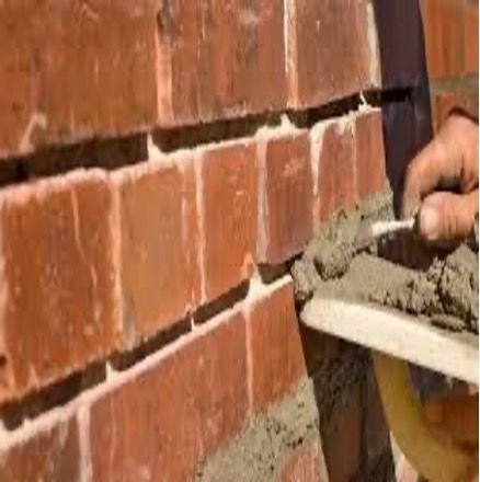Brick wall being repaired with mortar by hand using a trowel.